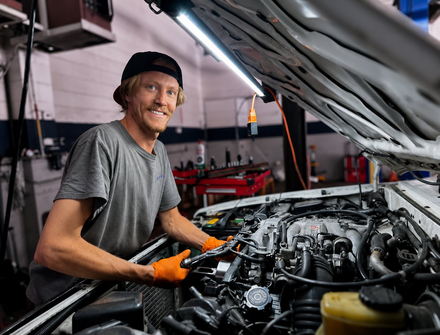 Nash smiling at the camera while working under the hood in his Tahoe City shop
